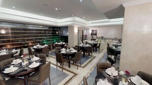 Un restaurant moderne doté de nombreuses tables pour accueillir les clients, avec un intérieur élégant caractérisé par un sol en marbre et un éclairage contemporain.