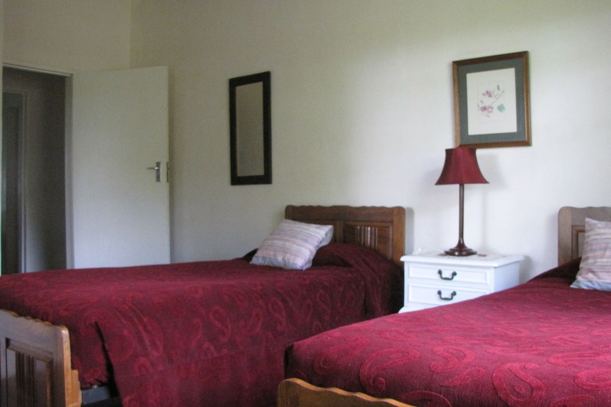 A bedroom with two beds, a nightstand, a lamp, and a framed picture on the wall.