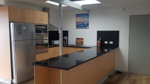 A kitchen with a refrigerator, oven, microwave, and a coffee maker.
