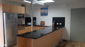 A kitchen with a refrigerator, oven, microwave, and a coffee maker.