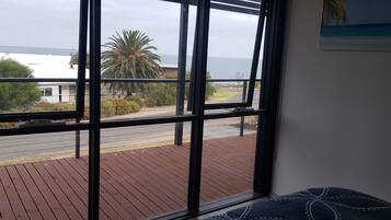 A room with a large window overlooking a wooden deck and a road.