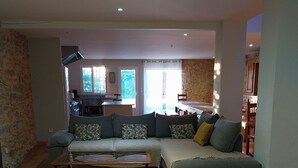 Un salon spacieux avec un grand canapé d’angle, une table basse et un mur en pierre.