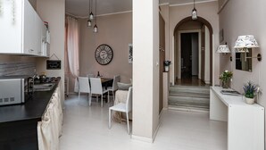 Een moderne keuken met een inbouwoven, een eethoek met een tafel en stoelen, en een gang die naar een trap leidt.