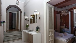 Een slaapkamer met een bed, nachtkastje, lamp en een spiegel.