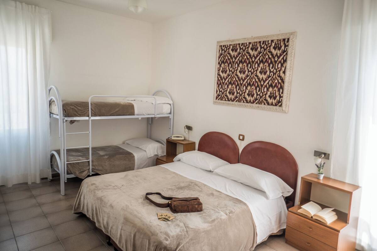A room with bunk beds, a bedside table with a lamp, and a wall-mounted artwork.