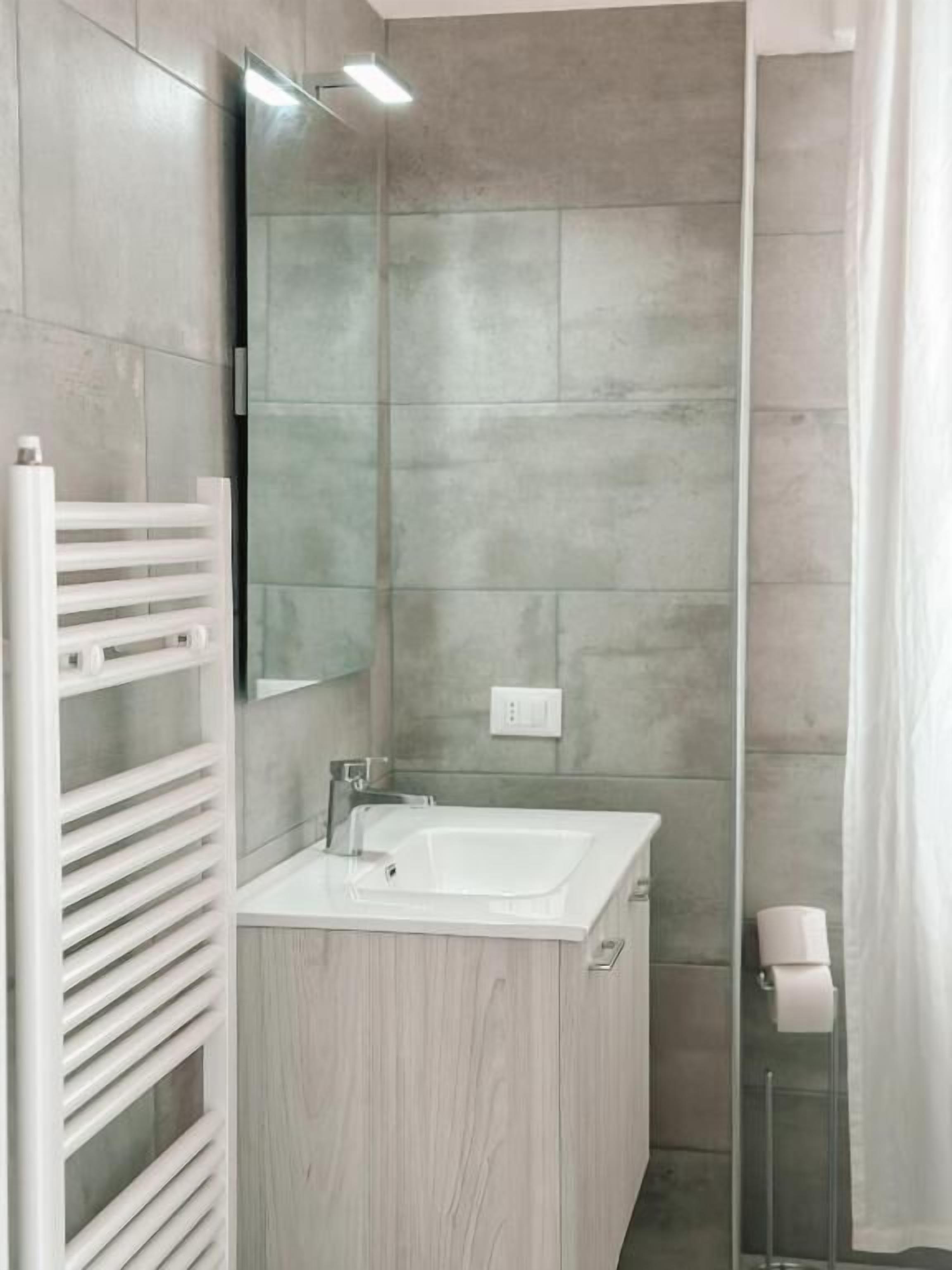 A modern bathroom with a white vanity, a mirror, and a shower area.