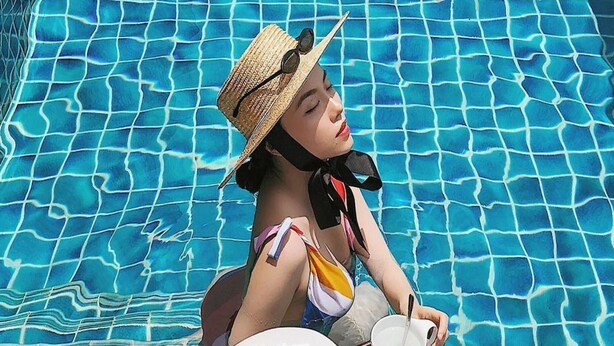 A person sitting by a pool with a tray of food. - Mega Light Hotel (Bac Nha Trang)