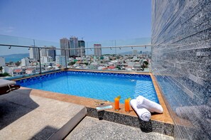 A rooftop pool with a city view, a magazine, and two drinks on the edge. - Mega Light Hotel (Bac Nha Trang)