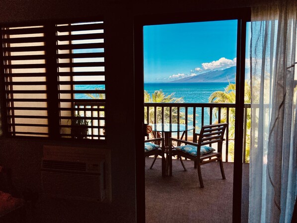 Una habitación con vista al océano a través de una ventana con persianas.