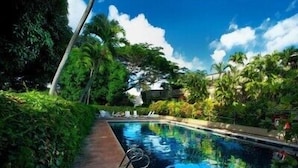 A swimming pool surrounded by lush greenery and a clear blue sky.