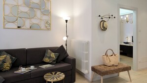 A modern living room with a dark brown sofa, a round coffee table, and a decorative wall piece. - Cavour 1 - New apartment at the lake (Salò)