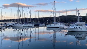 A marina with multiple sailboats docked, calm water, and a hilly landscape in the background. - Cavour 1 - New apartment at the lake (Salò)