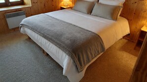 Una habitación con paneles de madera, una cama, un ventanal y un calefactor.