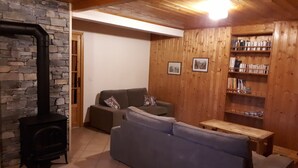 Una sala de estar acogedora con chimenea de piedra, un sofá gris y una estantería de madera.