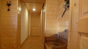 Un pasillo de madera con un banco y una puerta al final.
