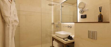 Un baño moderno con ducha acristalada, un espejo grande y un lavamanos con tocador.