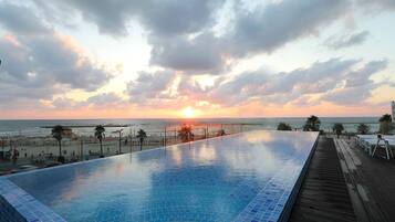 Ein Schwimmbad mit Blick auf den Sonnenuntergang über dem Meer.
