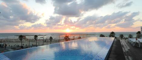 Una piscina con vista al atardecer sobre el océano.
