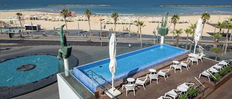 Ein Pool auf dem Dach mit Liegestühlen und Blick auf den Strand.