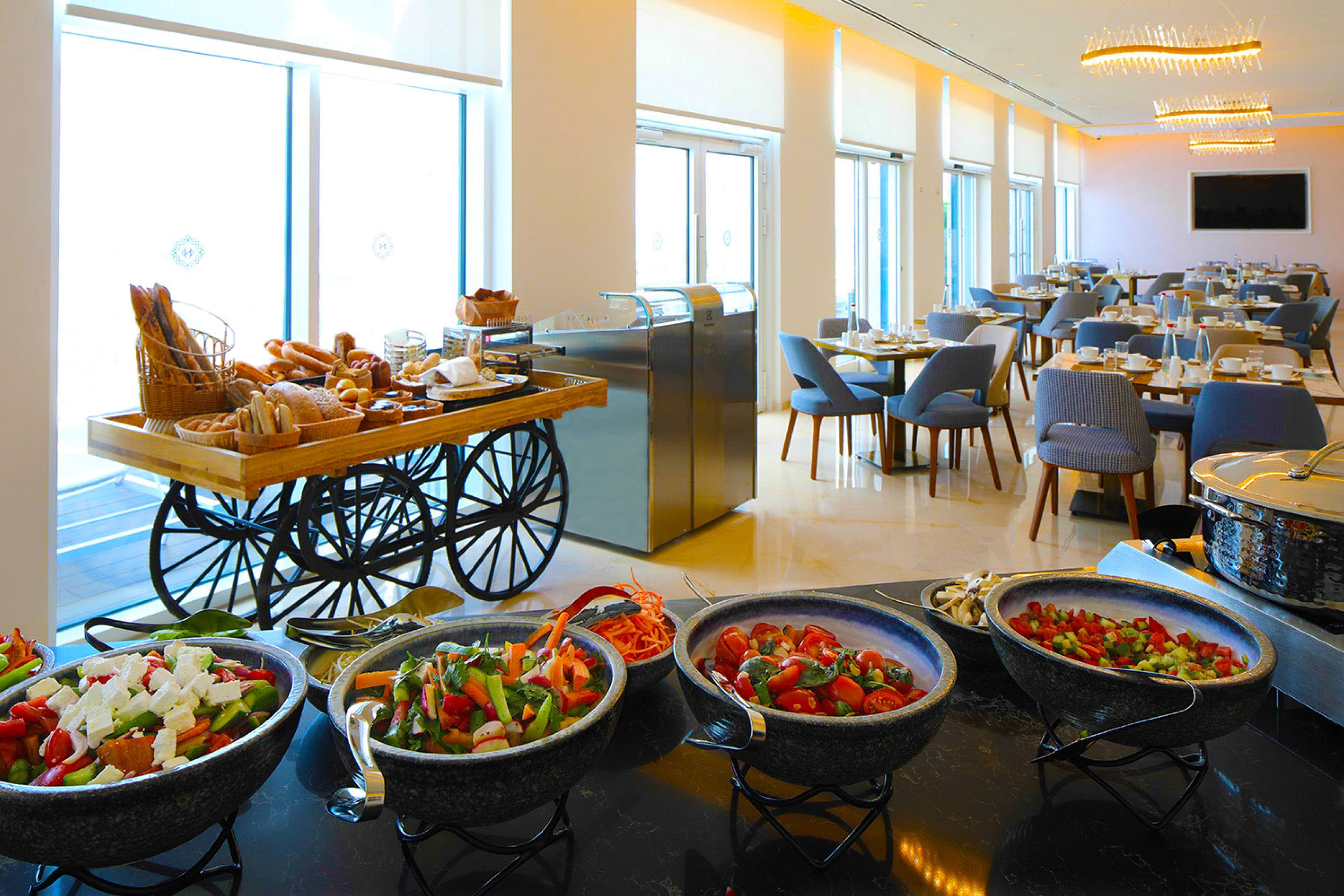 Un espace repas avec un buffet proposant une variété de plats et une sélection de pains.