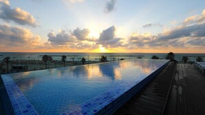 A infinity pool with a wooden deck and a view of the ocean at sunset. - Herbert Samuel Opera Tel Aviv (Tel Aviv)