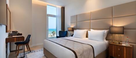 Una habitación de hotel moderna con una cama grande, un escritorio y vistas al océano.