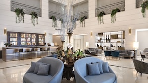 A spacious lobby with a central decorative tree, seating areas, a bar, and a well-lit reception desk. - Herbert Samuel Opera Tel Aviv (Tel Aviv)