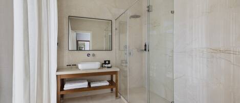 A modern bathroom with a glass-enclosed shower, a wooden vanity with a sink, and a large mirror.