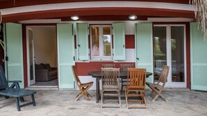 An outdoor patio with a table and chairs, a covered seating area, and a door leading to an interior space. - S102 - Sirolo, new three-room apartment with garden (Sirolo)