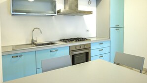A kitchen with a gas stove, sink, and stainless steel cabinets. - S102 - Sirolo, new three-room apartment with garden (Sirolo)