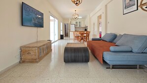 Ein geräumiger Wohnbereich mit einer Couch, einer Holzkommode und einem Esstisch.