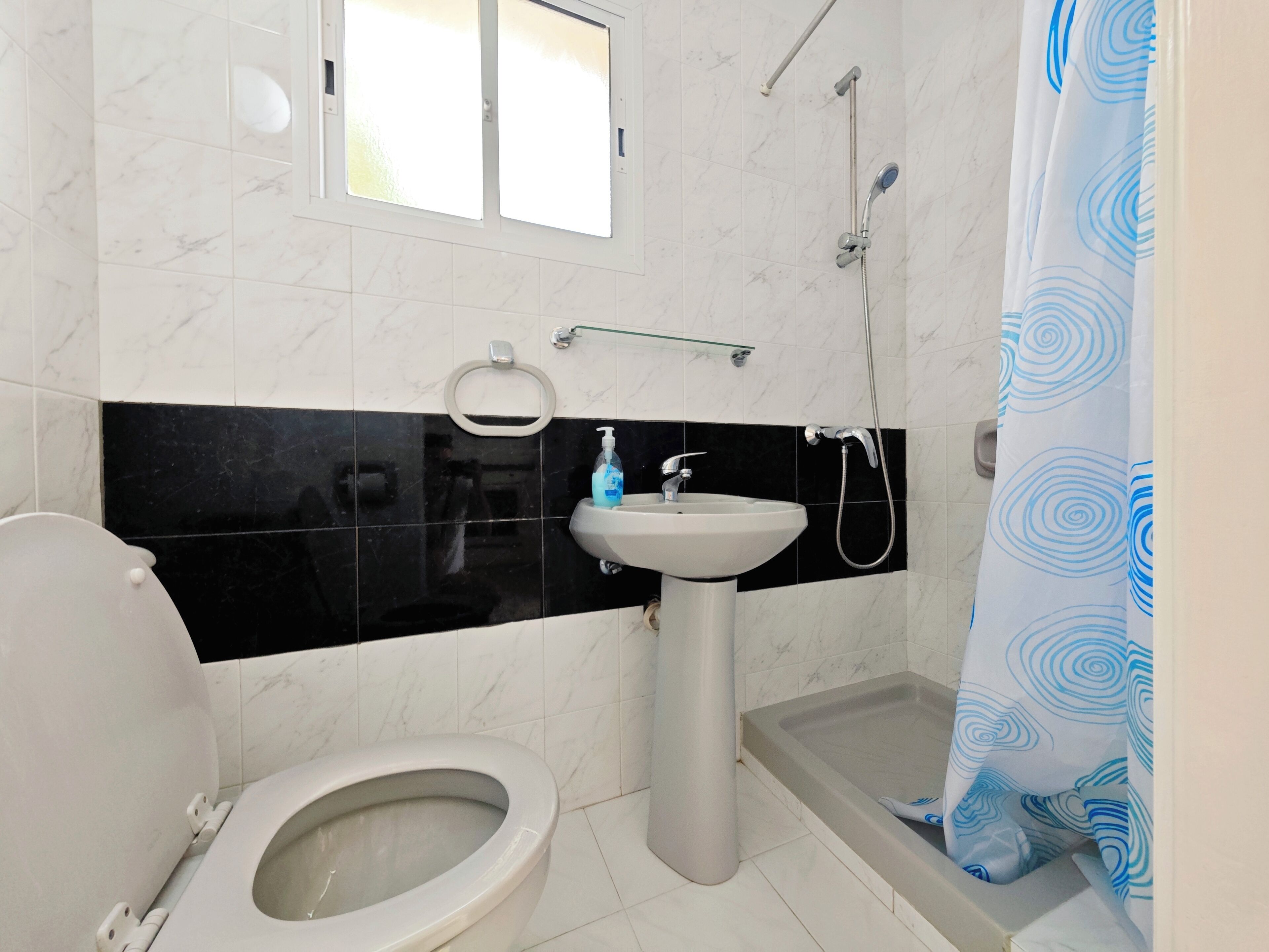 A bathroom with a toilet, sink, and shower.
