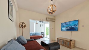 Ein modernes Wohnzimmer mit einer Couch, einem Fernseher und Blick ins Freie.