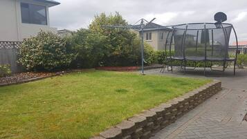 A residential garden with a lawn, a stone wall, and a metal structure.