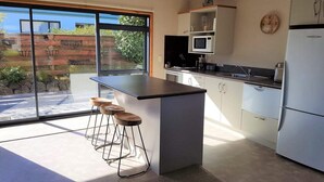 A modern kitchen with a central island, bar stools, a microwave, and a refrigerator. - View from Fletcher Street (Taupo)