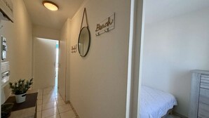 Un pasillo con una cama, un espejo y un letrero en la pared.