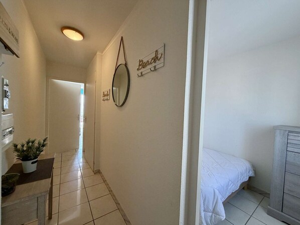 A hallway with a bed, a mirror, and a sign on the wall. - 2-room apartment, sea view balcony, private parking, Demoiselles Beach (Saint-Hilaire-de-Riez)