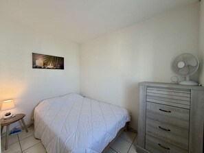 Een slaapkamer met een bed, een nachtkastje met een lamp, een kast en een aan de muur hangend schilderij.