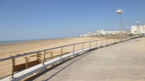 Un paseo marítimo con una pasarela de madera, barandales de metal y farolas.