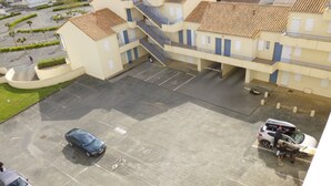 Un edificio de varios pisos con estacionamiento, una escalera y un pequeño jardín.