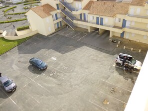 A multi-story building with a parking area, a staircase, and a small garden.
