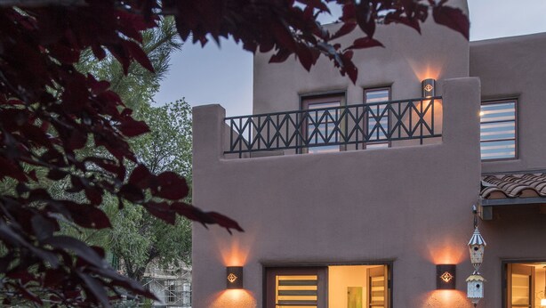 Un edificio moderno con un patio amueblado con mobiliario de mimbre y un farol decorativo.