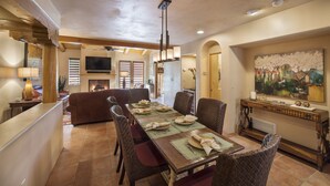 Comedor con una larga mesa de madera dispuesta para cuatro personas, rodeada de sillas de mimbre.