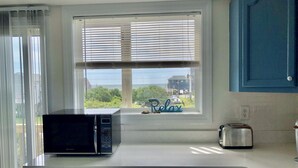 Een keuken met een magnetron op het aanrecht, een broodrooster en een raam met jaloezieën.