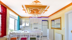 A modern kitchen with white cabinets, a central island, and a chandelier. - Seaside House (Ordu)