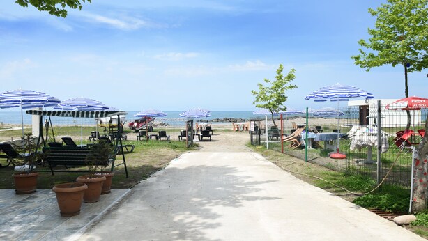 A beachside pathway leading to beach umbrellas and seating areas. - Seaside House (Ordu)