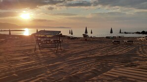 A beach with sun loungers, umbrellas, and a view of the sea and mountains during sunset. - Seaside House (Ordu)