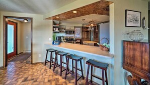 Cozinha com área de bar, banquetas de madeira e padrão de piso em herringbone.