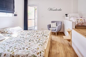 Ein Schlafzimmer mit einem Bett, einem Sessel, einer Holzauslage und einem Fenster mit Blick auf eine Ziegelwand.