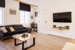 Ein modernes Wohnzimmer mit einer Couch, einem Couchtisch und einem an der Wand befestigten Fernseher.